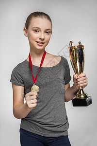 穿着运动服的微笑女孩拿着奖杯和灰图片