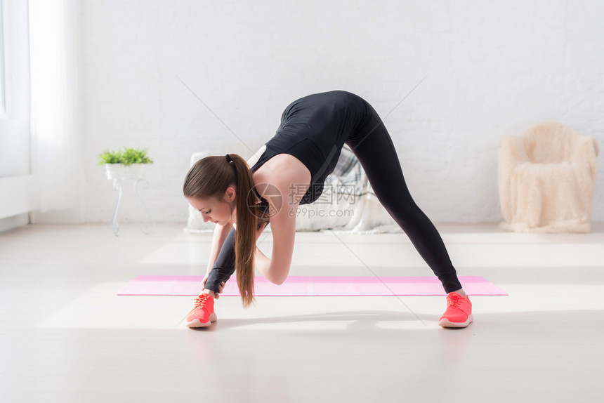 运动女做伸展运动她的腿筋和背部向前弯曲倾斜有氧运动或在图片