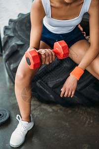 女运动员用哑铃和坐在健身房训练轮胎上锻炼运图片
