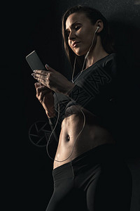 使用智能手机运动穿运动装的年轻运动员女图片