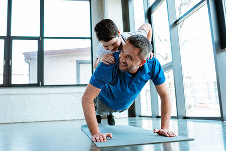 和儿子一起在健身房做运动的快乐父亲在体育馆用复制空间与儿子一图片