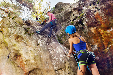 帮助少女登上山顶的女子攀岩教官帮助背景图片