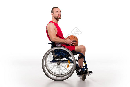 坐在轮椅上拿着篮球的残疾运动员的侧视图图片