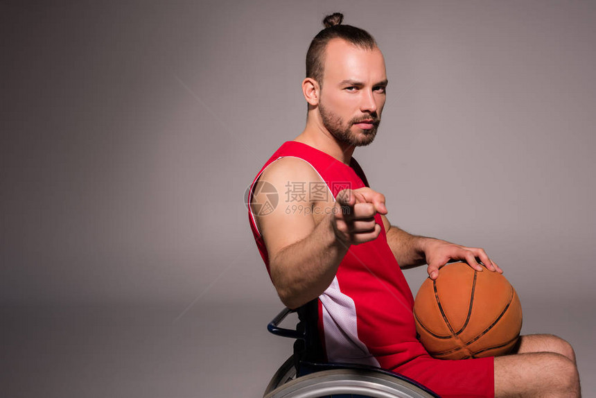 手持篮球和对着镜头的轮椅上残疾人运动图片