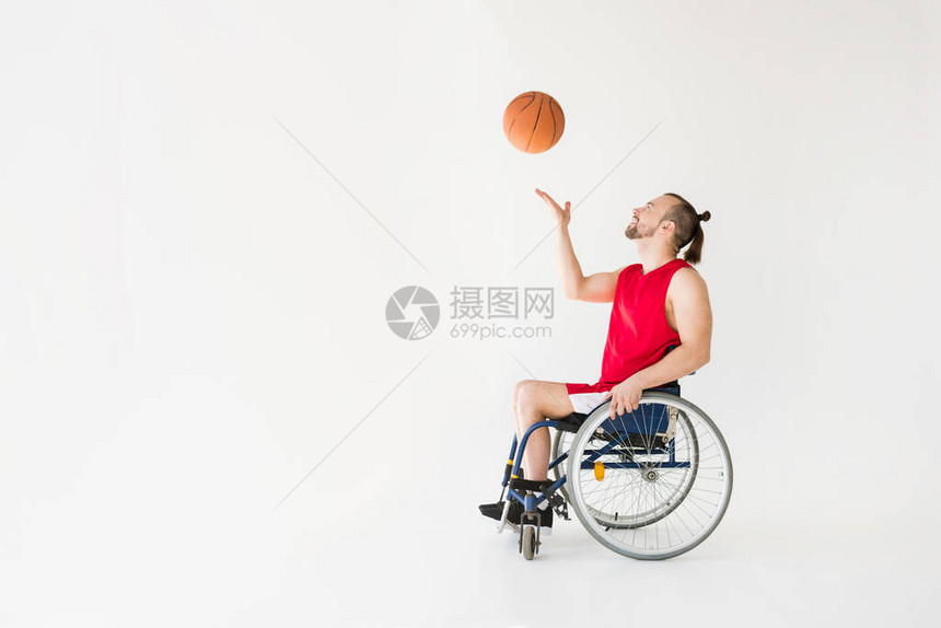 坐在轮椅打篮球微笑孤立在灰色上的残图片