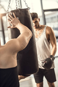 拳击手在健身房训练时教练拿着沙袋图片