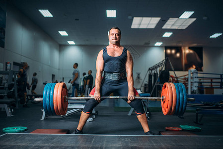 强壮的举重运动员在背景上用杠铃硬拉健身房内部锻炼在运动或健身俱乐部的举竞技高清图片素材