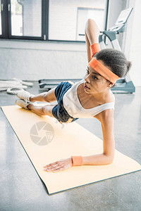 身戴头带和手腕带的年轻美国女运动员在健身房健身垫图片