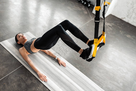 体育女孩悬吊在健身带和健身瑜伽垫上训图片