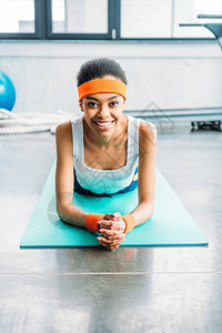戴着头带和腕带的非洲裔美国女运动员微笑着躺在健身图片