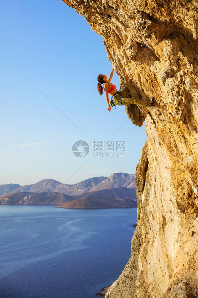 女攀岩者在挑战路线上仰望悬崖图片