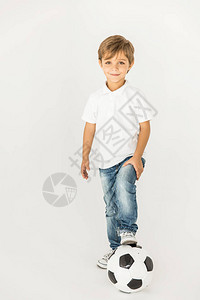 可爱的小可爱男孩站在足球旁边看着在白色上图片