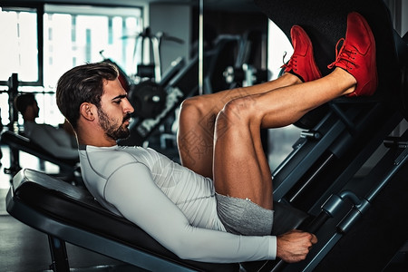 男人专注于在健身房的机器上训练腿图片