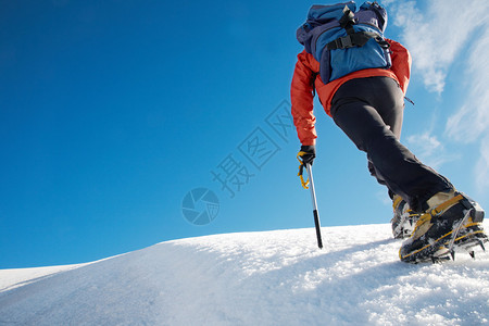孤独的男登山者攀登雪脊图片