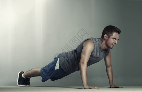 穿着运动服的男运动员做俯卧撑背景图片