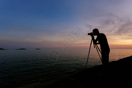 摄影师或旅行者使用专业数码单反相机的剪影图片