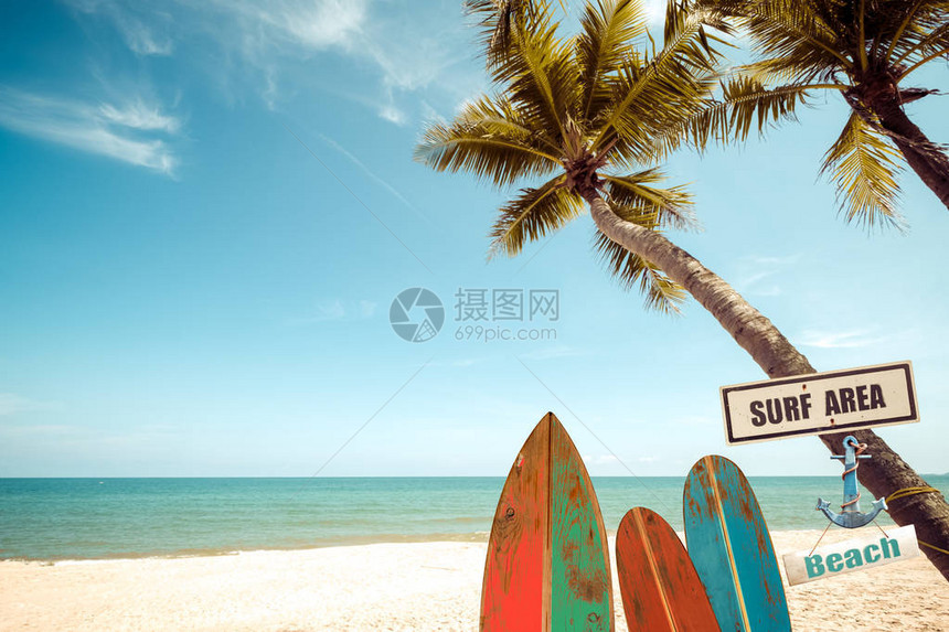 夏季热带海滩上带棕榈树的复古冲浪板复古色调图片