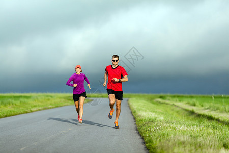 男运动员和女跑者在乡村公路上奔跑图片