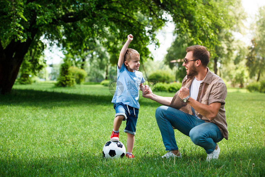 快乐的父亲和儿子在公园踢足球后图片