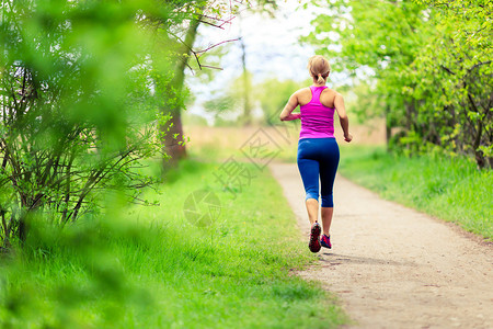 女子赛跑者在乡间小路上的公园里与狗一起跑步图片