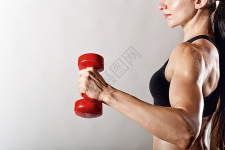 灰色背景上带杠铃的健身女人图片