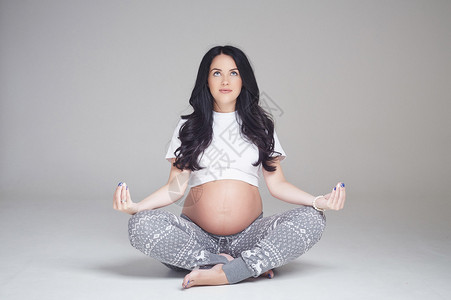 怀孕的黑发女人盘腿坐在地板上图片