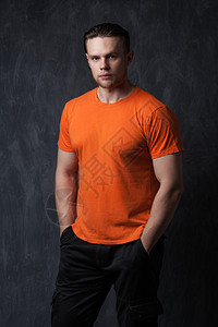 身穿橙色衬衫的强壮男子将双手套在口袋里灰图片