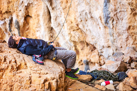 年轻人躺在石头上看着领先的攀岩背景图片