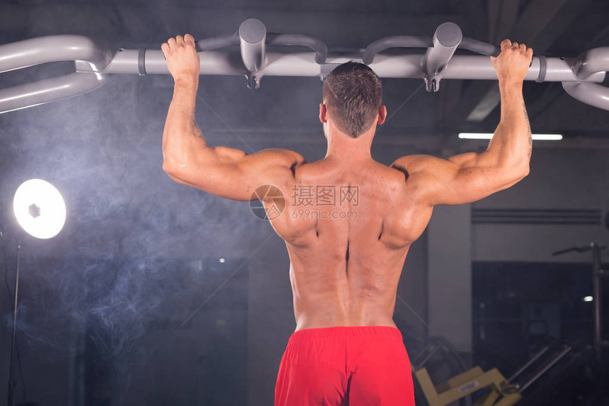 在健身房的横向酒吧上拉吊的男运动肌图片