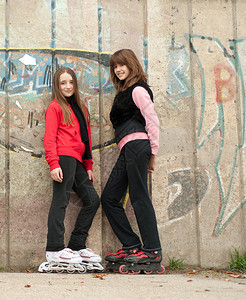 两个笑着的少女穿着溜冰滑雪鞋站在水泥图片
