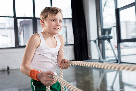 体育训练中可爱的男孩在健身工作室用绳子做运动服装训练图片