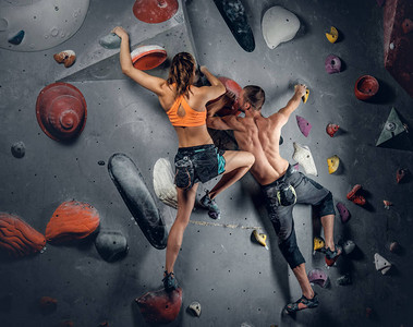 在攀岩墙上攀爬的运动型男女图片