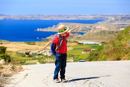 小男孩在风景路上玩背包旅行图片