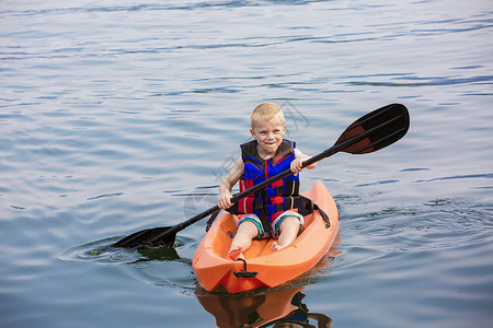 在湖上划皮艇的年轻男孩从上面查看以及图片