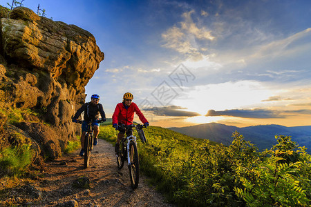 山地自行车妇女和男子骑自行车在日落山林景观情侣骑自行车MTBenduro流径赛道户外的高清图片素材