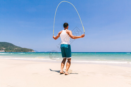 在海边用绳子跳过沙滩的健身人与蓝天图片