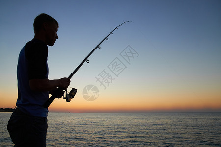 渔民在湖边钓鱼日落图片