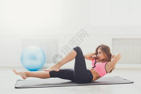 躺在健身房赤脚做仰卧起坐的健身女人年轻的型女孩在垫子上做仰卧起坐健康生活方式体背景图片