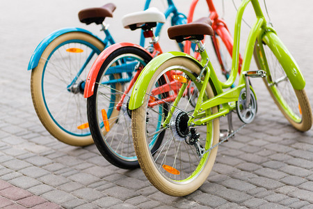 三辆美丽的女士城市亮彩色的自行车或自行车妇女站在夏日公园露图片