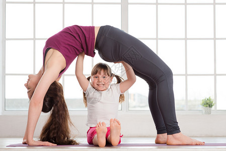 年轻母亲和女儿在健身工作室做瑜伽锻炼图片