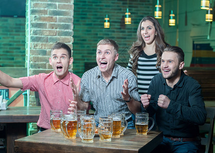 三个男人和一个女孩喝啤酒欢庆他们最喜欢的球队图片