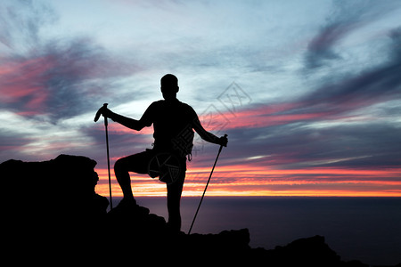 男人在山上日落和海洋中徒步旅行图片