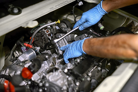 一名身戴蓝手套的机械工手在一辆汽车发动机上工作图片