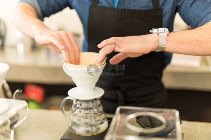 关闭男咖啡厅在咖啡馆煮咖啡时将过滤图片