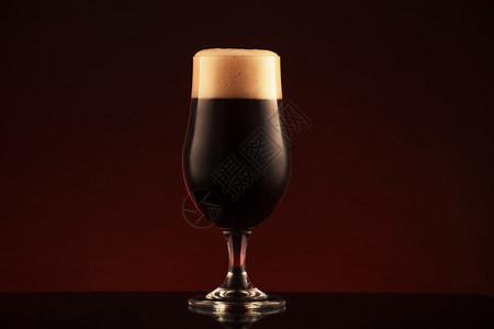 杯在棕色背景的黑啤酒背景图片