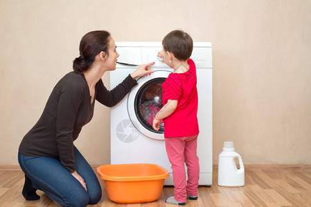 母亲教小女孩怎么用洗衣机图片