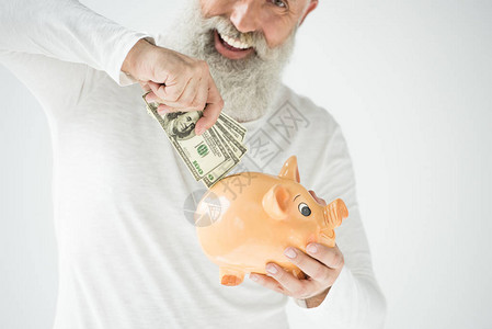 带着美元钞票和小猪银行的快乐长胡子大胡子老人图片