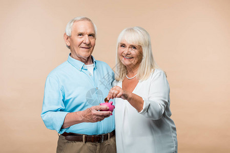 快乐的退休男人拿着粉红银行而老太却在蜜蜂上把图片