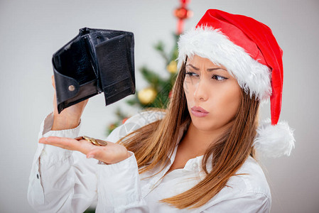 年轻漂亮的女商人戴着圣诞老人的帽子看着空钱背景图片