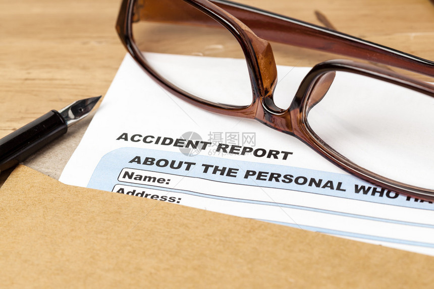 有关棕色信封和眼镜商业保险和风险概念的事故报告申请表和纸笔图片